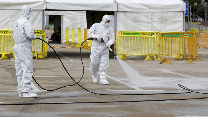 Israeli firefighters spray disinfectant at a COVID-19 drive-through testing site in Tel Aviv on March 20.