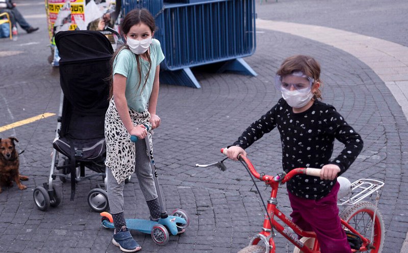 In this March 24, 2020 photo, children wear protective face masks amid concerns over the country’s coronavirus outbreak in Tel Aviv, Israel.